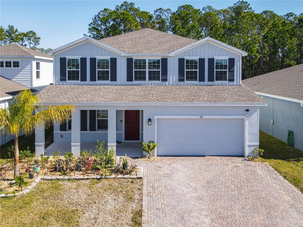A two-story house with a light gray exterior, a red front door, and a paved driveway — 121 EAGLE HARBOR WAY, DAYTONA BEACH, FL