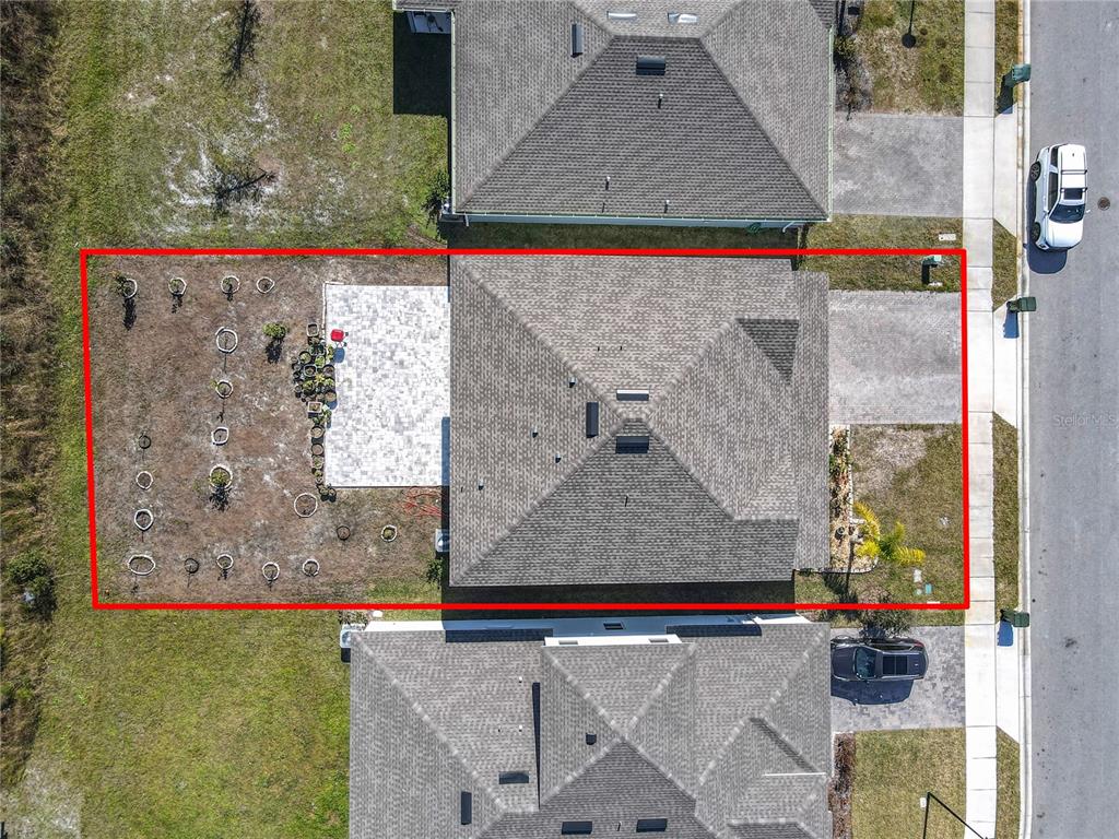 An aerial view shows a house with a paved patio and a fenced backyard — 121 EAGLE HARBOR WAY, DAYTONA BEACH, FL
