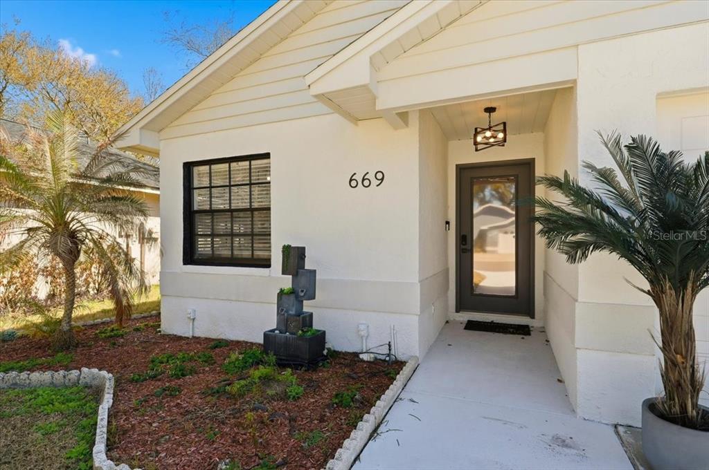 The exterior of a house features a white facade, a dark front door, and landscaping — 669 EAGLE RUN, LAKELAND, FL
