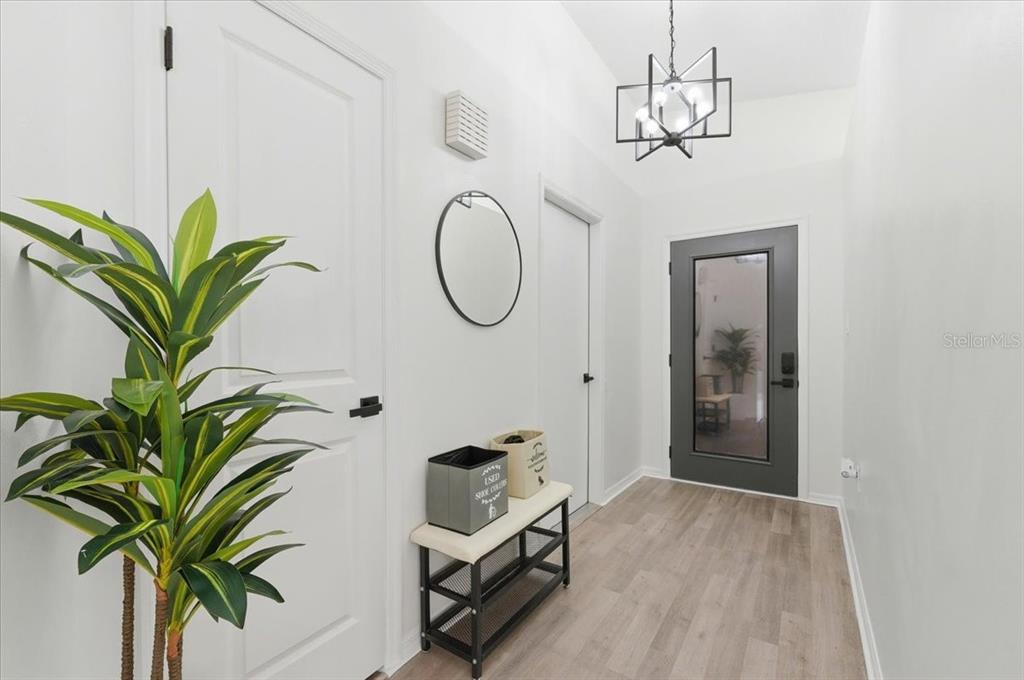 A bright entryway features a gray front door, a bench, a mirror, and a chandelier — 669 EAGLE RUN, LAKELAND, FL