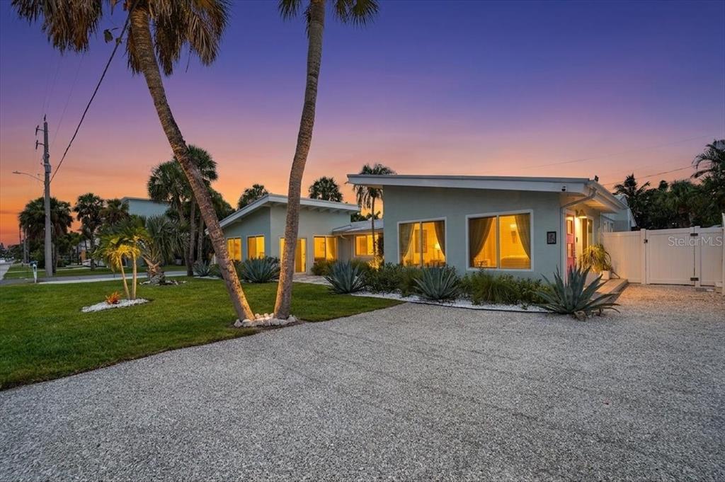 A single-story house with a gravel driveway and palm trees at sunset — 6203 HOLMES BOULEVARD, HOLMES BEACH, FL
