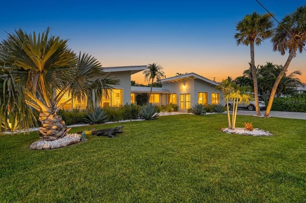 A modern single-story house with a grassy lawn, palm trees, and an alligator statue — 6203 HOLMES BOULEVARD, HOLMES BEACH, FL