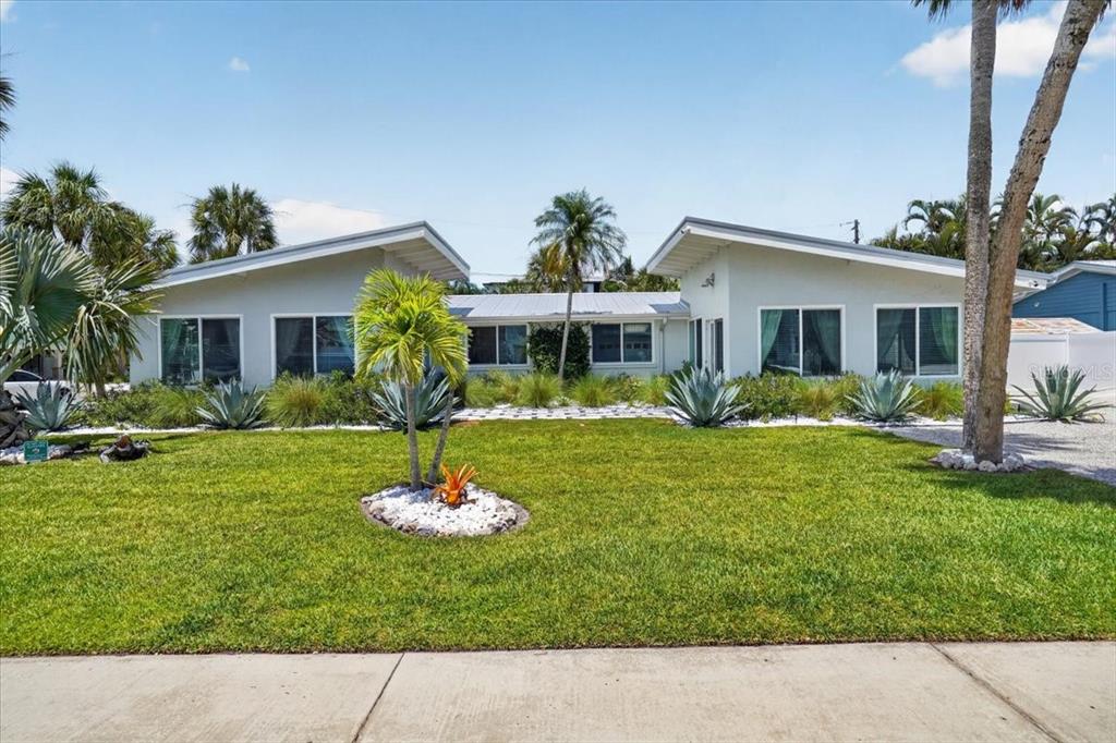 A single-story house with a butterfly roof and a landscaped front yard with palm trees — 6203 HOLMES BOULEVARD, HOLMES BEACH, FL