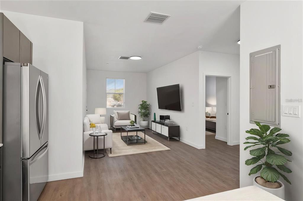 A modern living room features wood-look flooring, a wall-mounted television, and an open floor plan — 1581 NW 29TH ROAD UNIT 8, GAINESVILLE, FL