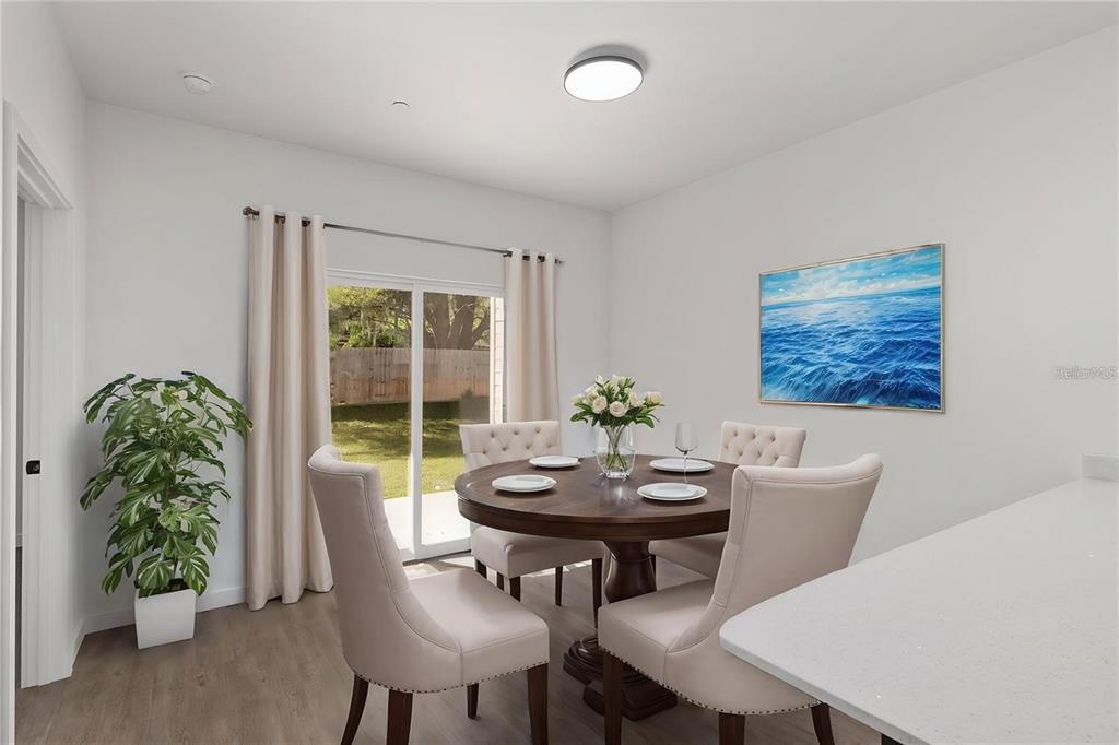 A dining room features a round wooden table, four upholstered chairs, and a sliding glass door — 1581 NW 29TH ROAD UNIT 8, GAINESVILLE, FL
