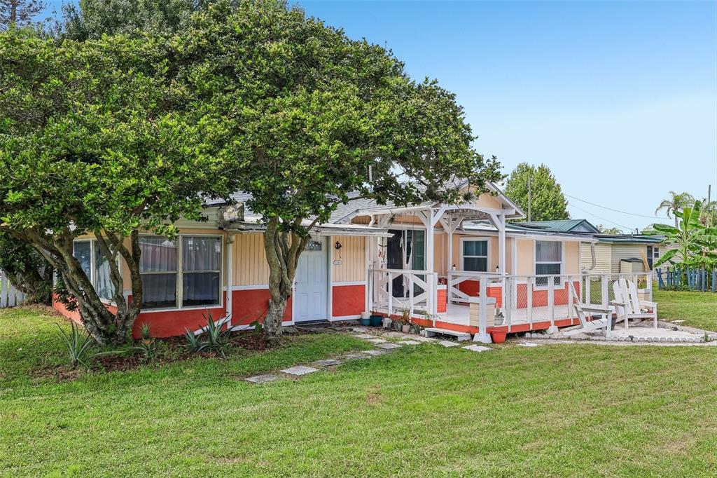 A single-story house with yellow and orange siding, a white front door, and a wooden deck — 6281 BASS HIGHWAY, ST CLOUD, FL