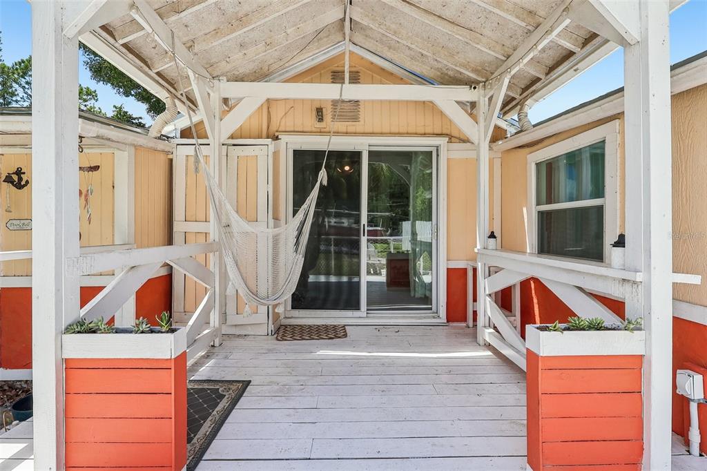 A covered wooden porch features a white hammock, orange-painted railings, and sliding glass doors — 6281 BASS HIGHWAY, ST CLOUD, FL