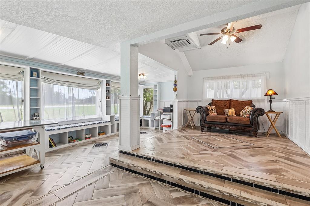 A living room features a raised platform with herringbone tile flooring and a brown sofa — 6281 BASS HIGHWAY, ST CLOUD, FL