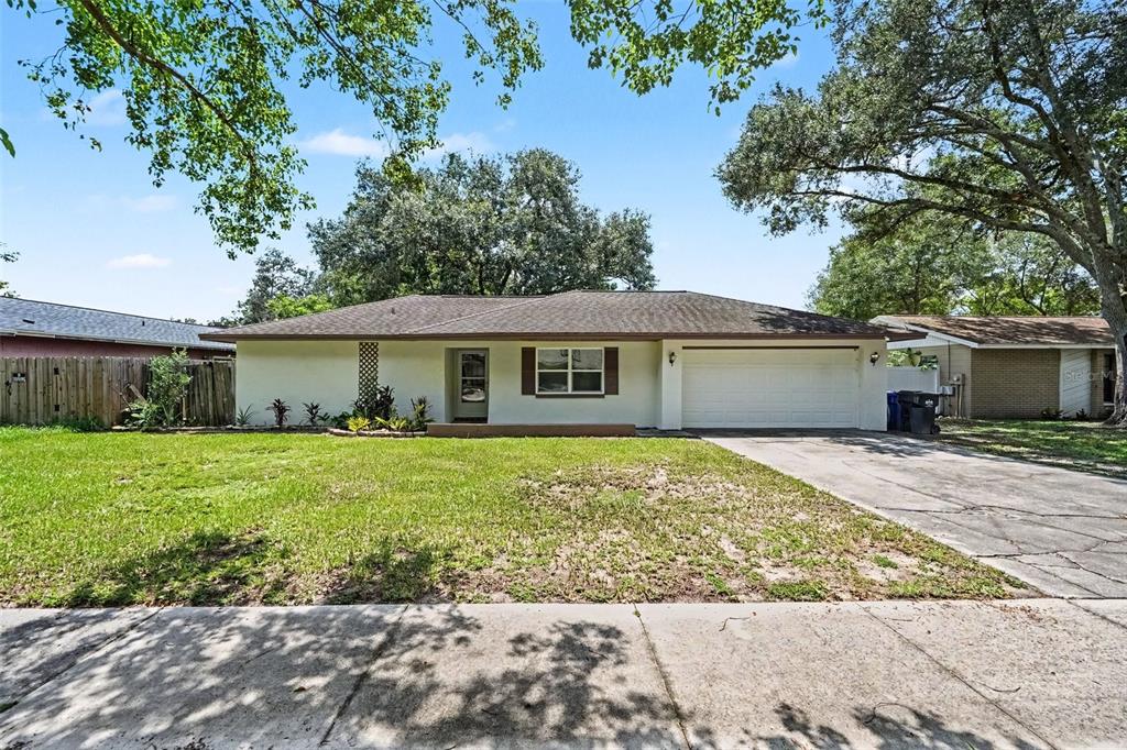 A single-story house with a white exterior, a two-car garage, and a front lawn — 1913 CEDARBROOKE DRIVE, LUTZ, FL