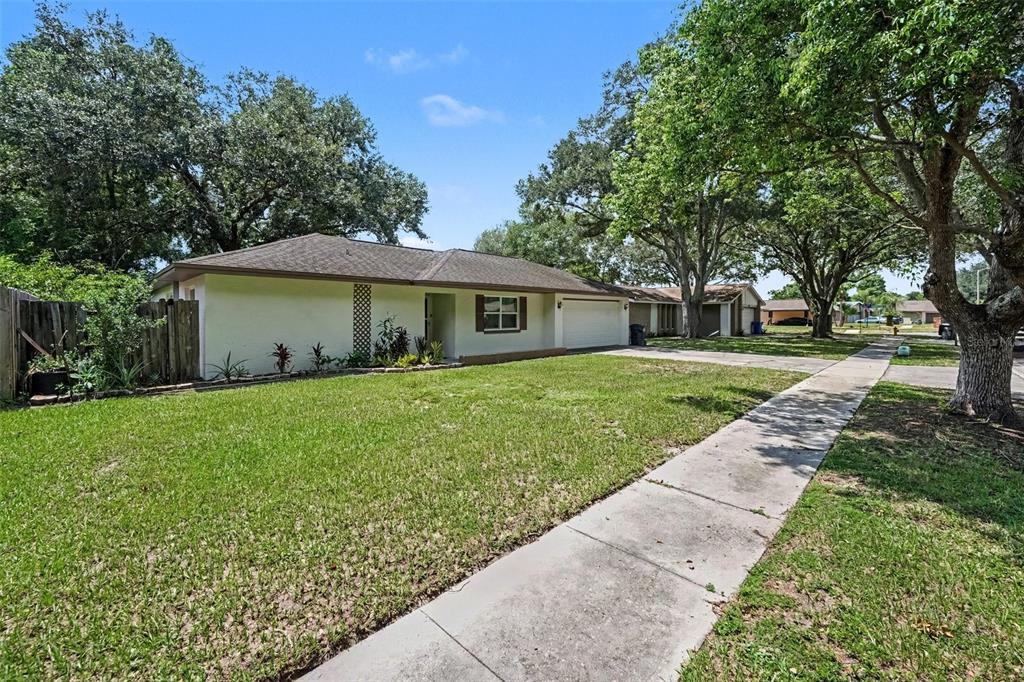 A single-story house with a white exterior, a garage, and a sidewalk in the front yard — 1913 CEDARBROOKE DRIVE, LUTZ, FL