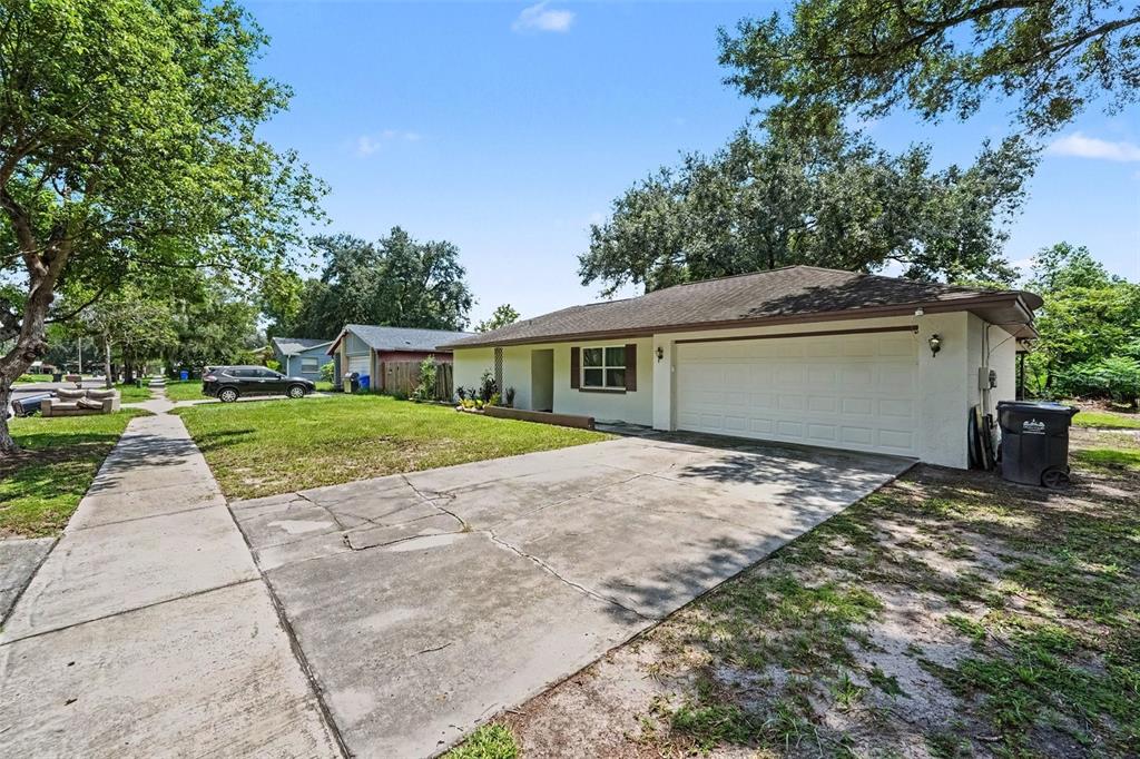 A single-story house with a white exterior, a two-car garage, and a cracked concrete driveway — 1913 CEDARBROOKE DRIVE, LUTZ, FL