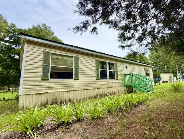 A light-colored mobile home with a metal roof and a small green wooden porch — 4760 NW 55TH AVENUE, BELL, FL