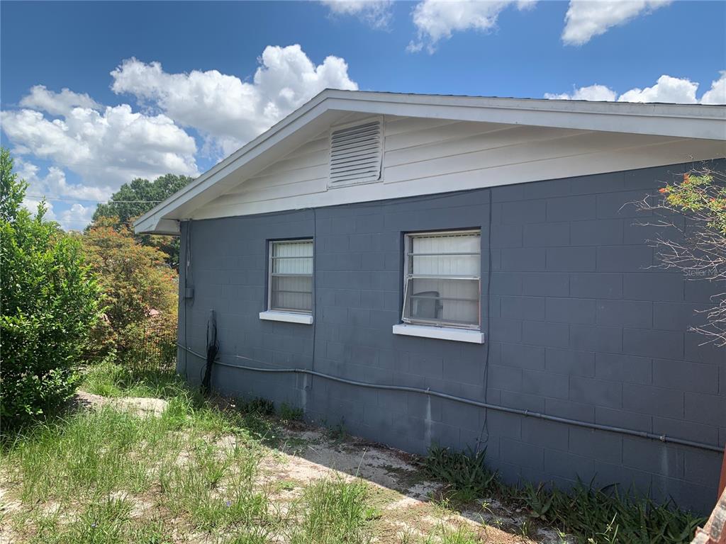 The exterior of a gray concrete block house features two windows and a white gable — 119 ALLEN AVENUE, WINTER HAVEN, FL