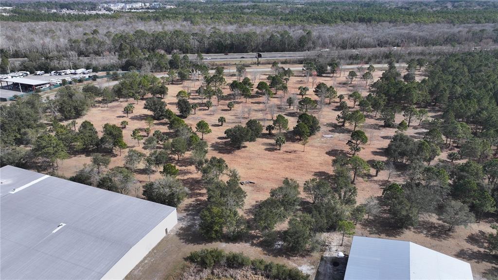An aerial view shows a large, partially wooded vacant lot adjacent to two industrial buildings — AGRICULTURAL CENTER DRIVE, ST AUGUSTINE, FL