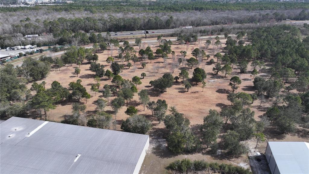 An aerial view shows a large, partially wooded vacant lot adjacent to commercial buildings — AGRICULTURAL CENTER DRIVE, ST AUGUSTINE, FL
