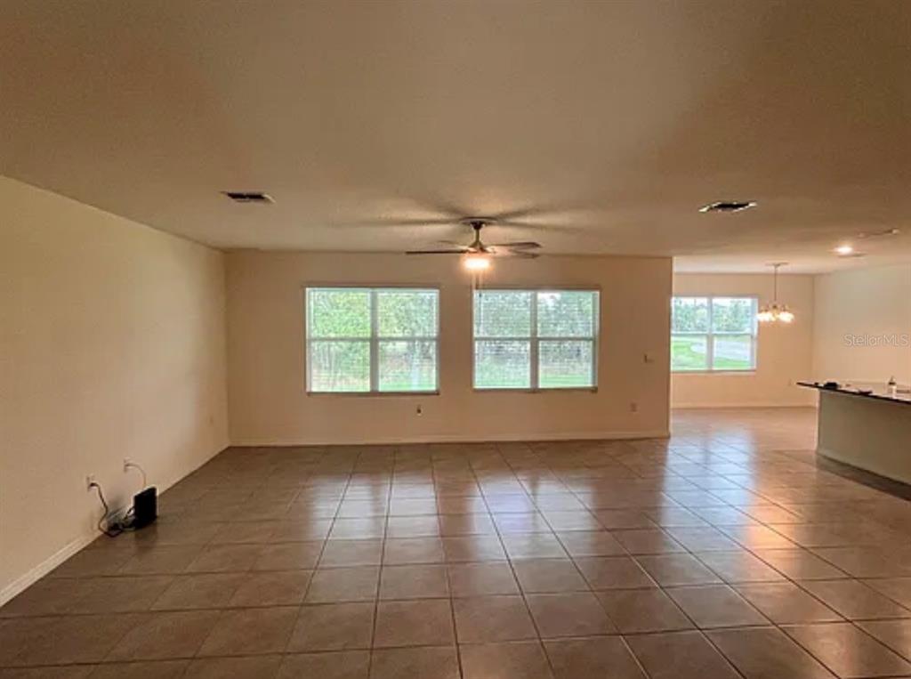 A spacious living room features light-colored walls, tile flooring, and a ceiling fan — 5 HICKORY COURSE LOOP, OCALA, FL