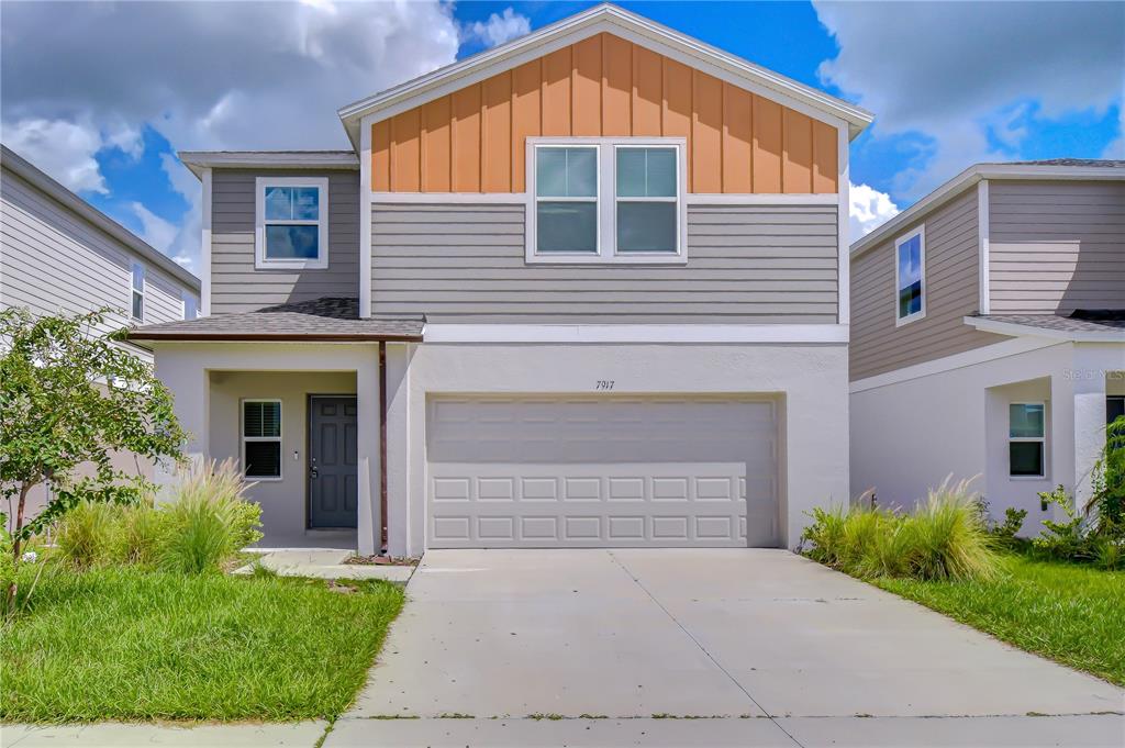 A two-story suburban house features a gray and orange facade with a two-car garage — 7917 PEACE LILY AVENUE, WESLEY CHAPEL, FL
