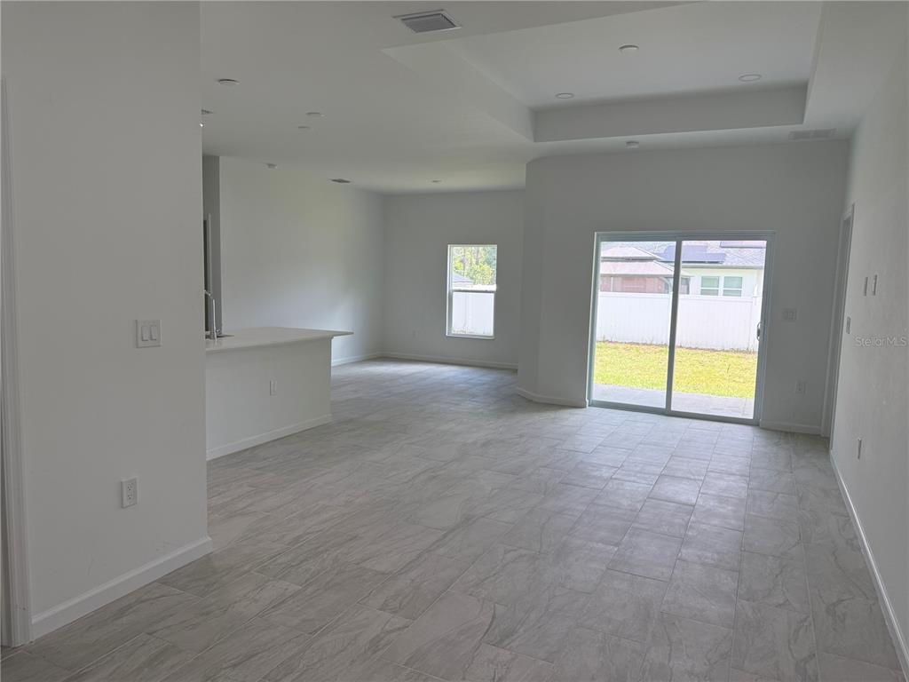 An open-concept living area features light gray tile flooring, a kitchen island, and sliding glass doors — 2964 WELLS AVENUE, NORTH PORT, FL