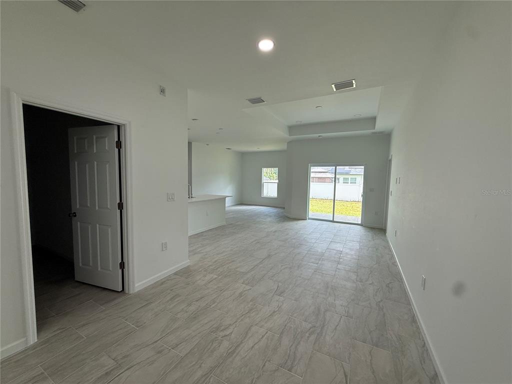 An open-concept living area features light-colored tile flooring, white walls, and a sliding glass door — 2964 WELLS AVENUE, NORTH PORT, FL