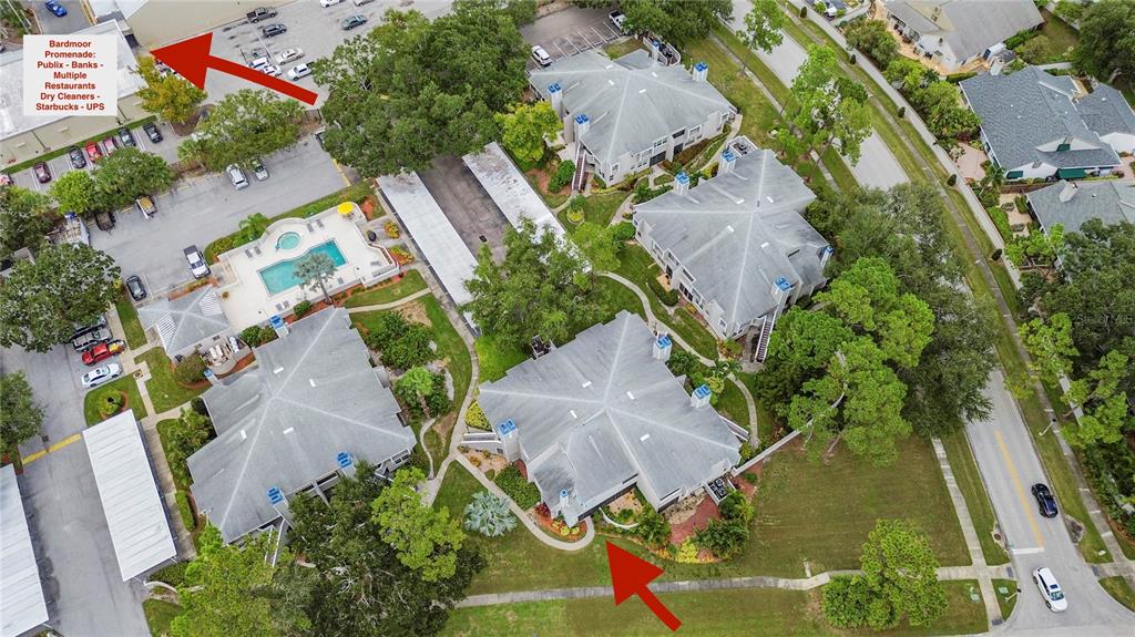 An aerial view shows residential buildings, a swimming pool, parking areas, and nearby commercial shops — 8707 BARDMOOR PLACE UNIT 101, SEMINOLE, FL