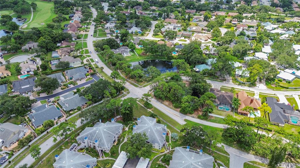 An aerial view shows a suburban neighborhood with houses, a small pond, and roads — 8707 BARDMOOR PLACE UNIT 101, SEMINOLE, FL