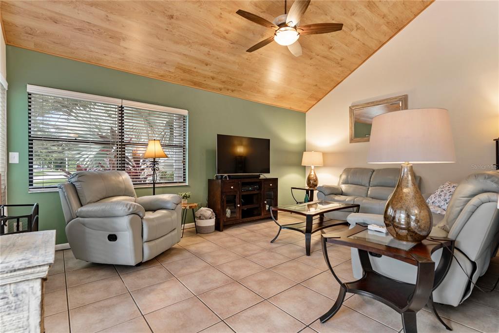 A living room features a vaulted wood ceiling, tiled floors, and a green accent wall — 8707 BARDMOOR PLACE UNIT 101, SEMINOLE, FL