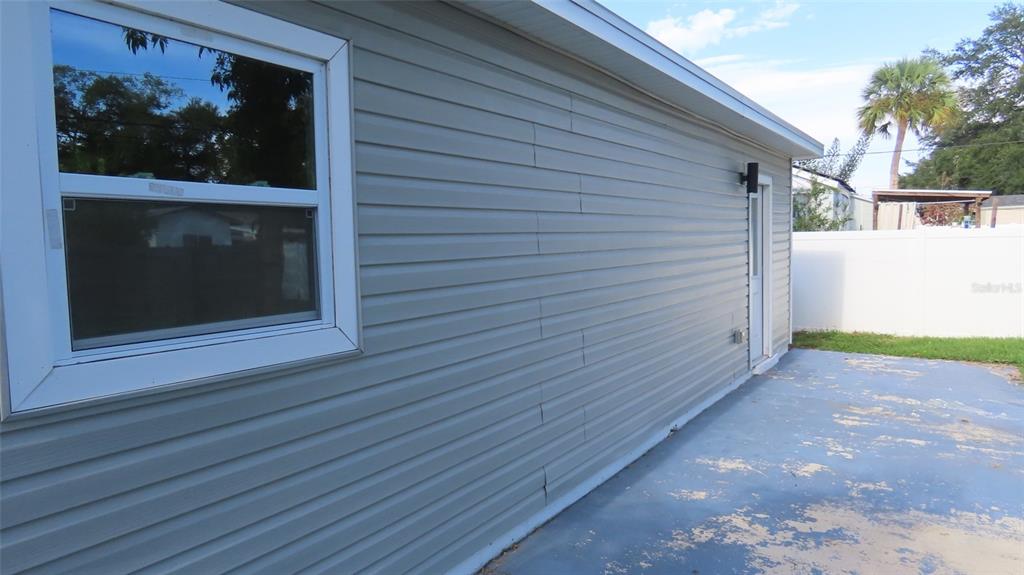 A side view of a house exterior featuring gray vinyl siding, a window, and patio — 5318 9TH AVENUE N, ST PETERSBURG, FL