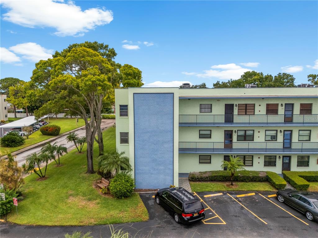 An exterior view of a multi-story apartment building with a blue accent wall and parking — 5973 TERRACE PARK DRIVE N UNIT 101, ST PETERSBURG, FL