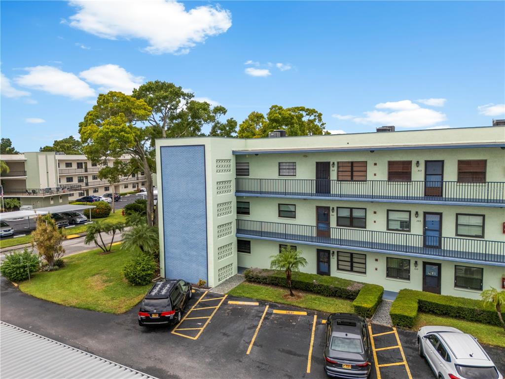 An outdoor hallway features a brick wall, an elevator, and a seating area with chairs — 5973 TERRACE PARK DRIVE N UNIT 101, ST PETERSBURG, FL