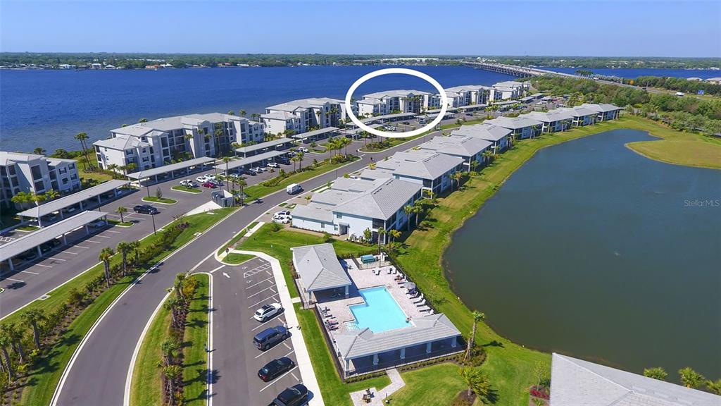 An aerial view shows a multi-story apartment complex with a pool and waterfront access — 1010 TIDEWATER SHORES LOOP UNIT 406, BRADENTON, FL