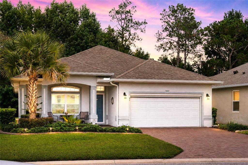 A single-story house with a white stucco exterior, a two-car garage, and a palm tree — 91 PARK PLACE CIRCLE, PALM COAST, FL
