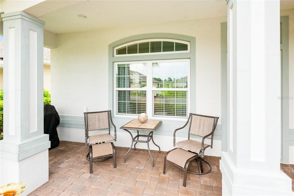 A covered patio features two chairs, a small table, and a window with an arched transom — 91 PARK PLACE CIRCLE, PALM COAST, FL