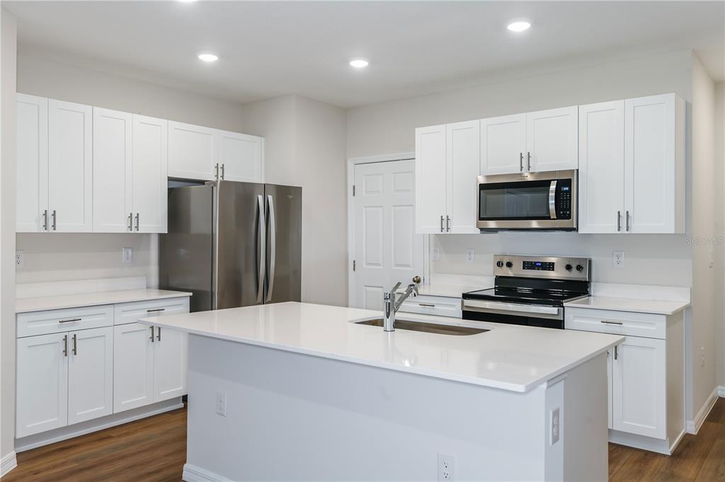 A modern kitchen features white cabinetry, stainless steel appliances, and a large central island — 4255 HILLOCK BOULEVARD, HAINES CITY, FL