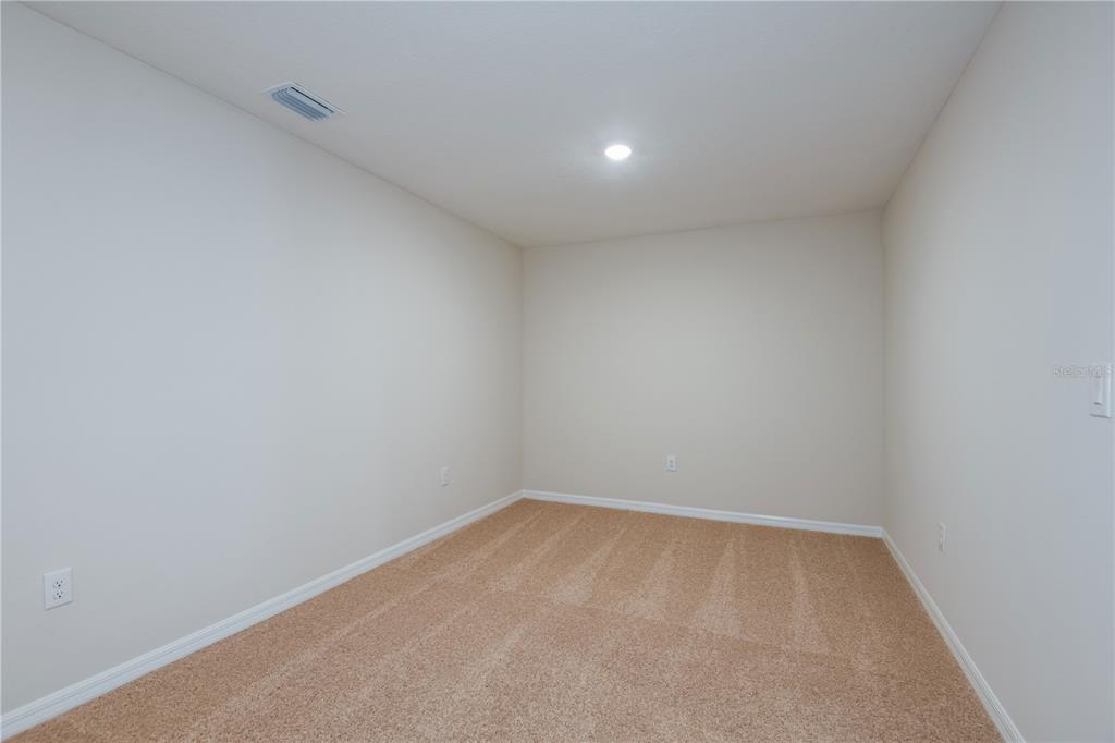 An empty room with beige carpet, light-colored walls, a single ceiling light, and an air vent — 4255 HILLOCK BOULEVARD, HAINES CITY, FL