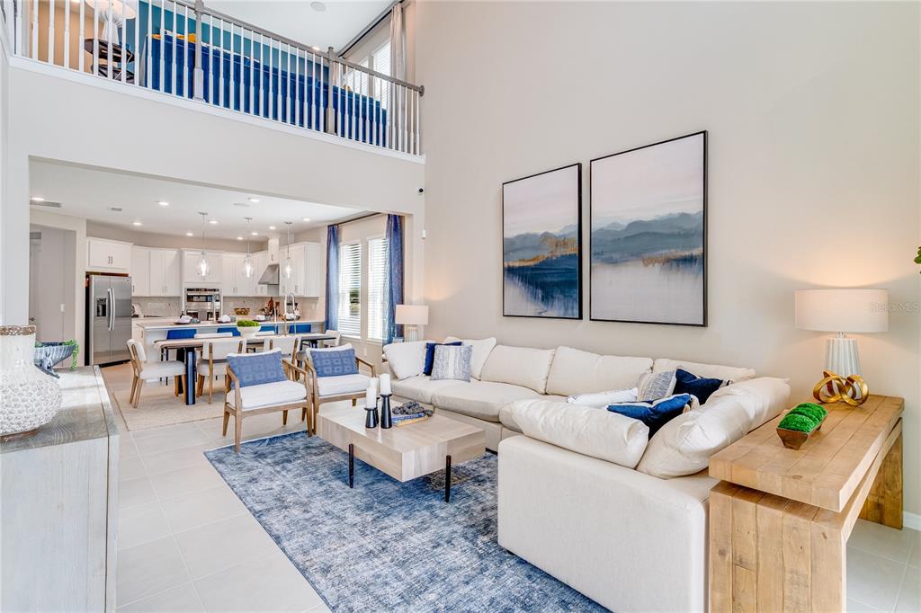 A modern kitchen features white cabinetry, stainless steel appliances, a center island, and blue barstools — 1224 TEAL CREEK DRIVE, ST CLOUD, FL