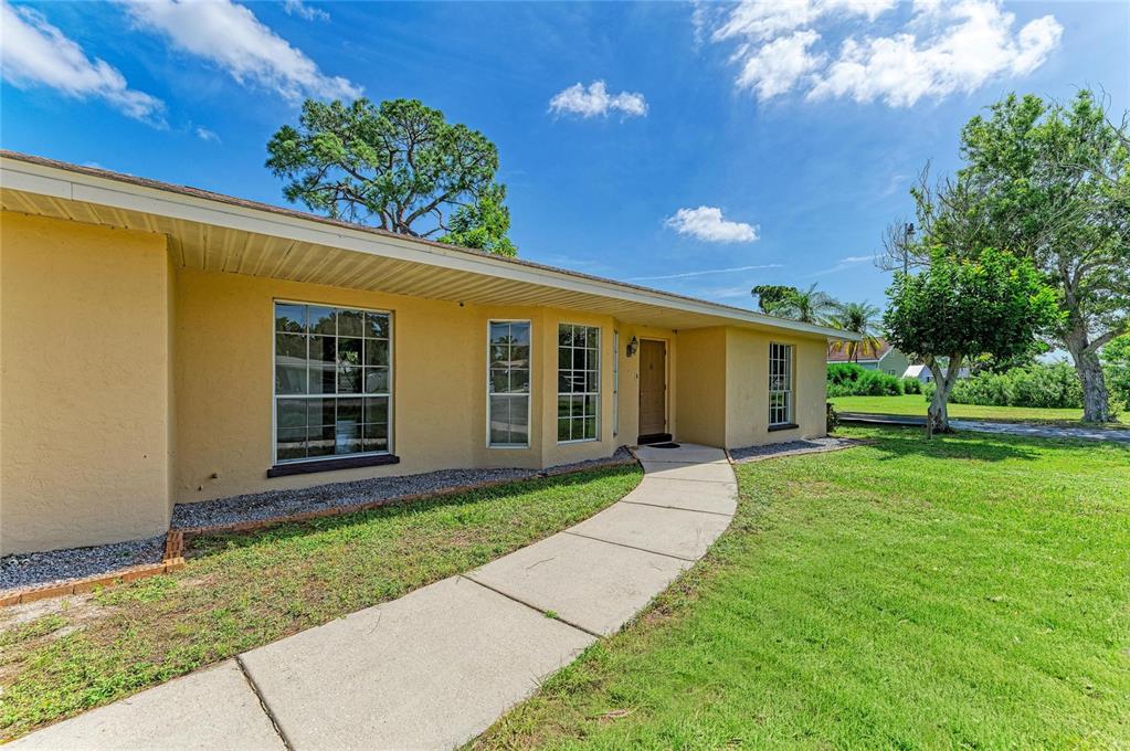 A yellow single-story house with a concrete walkway leading to the front entrance — 4404 18TH AVENUE W, BRADENTON, FL