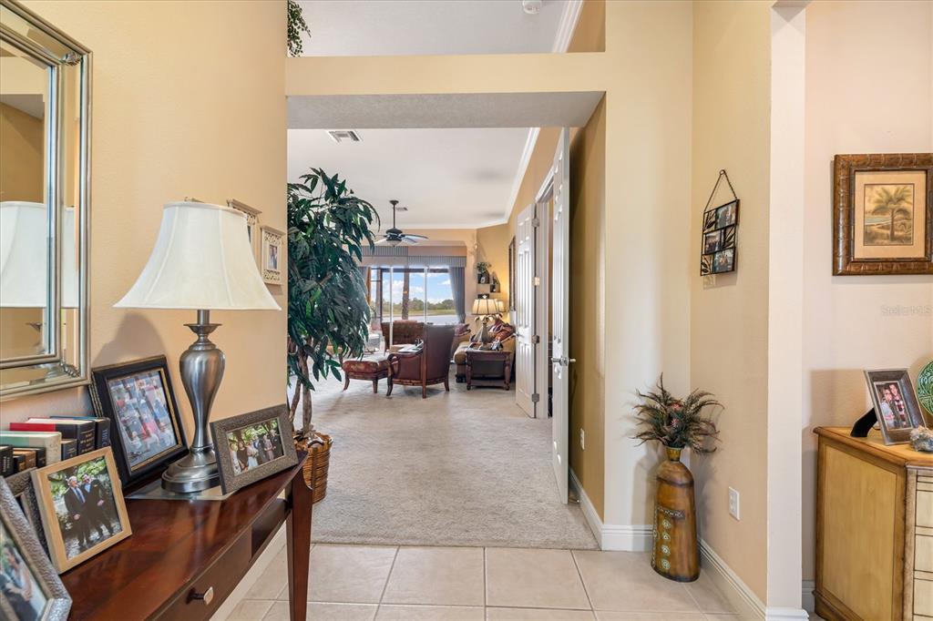 A tiled entryway leads into a carpeted living area with a view of a lake — 23126 COPPERLEAF DRIVE, VENICE, FL