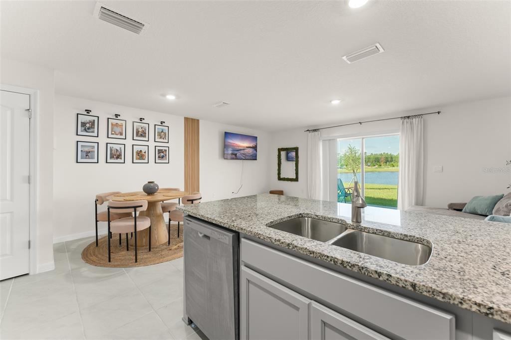 A kitchen island with a granite countertop overlooks a dining area and a sliding glass door — 2834 BRIE HAMMOCK BEND, ST CLOUD, FL