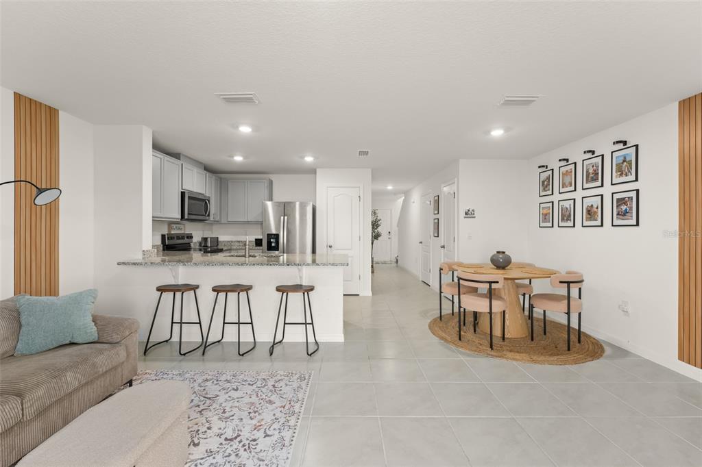 An open-concept kitchen and dining area features light gray cabinets, stainless appliances, and tile flooring — 2834 BRIE HAMMOCK BEND, ST CLOUD, FL