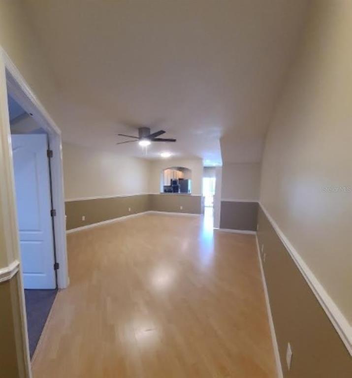 An open-concept room features light wood flooring, two-toned walls, and a ceiling fan — 15746 STABLE RUN DRIVE, SPRING HILL, FL