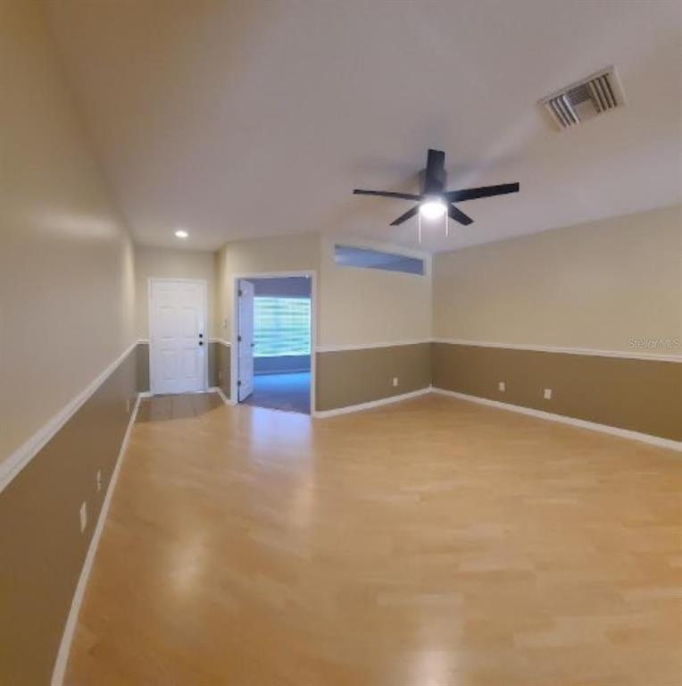 An empty room with light wood flooring, two-tone walls, a ceiling fan, and a doorway — 15746 STABLE RUN DRIVE, SPRING HILL, FL