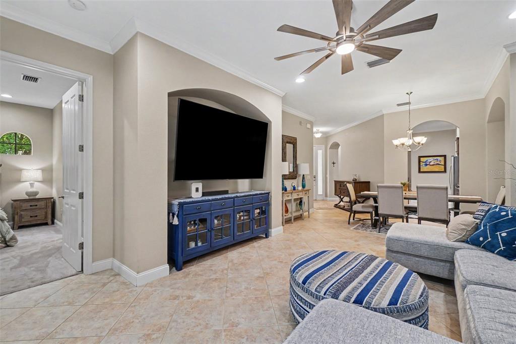 A living room features a blue media console, a large television, and tile flooring — 6103 25TH STREET E, ELLENTON, FL