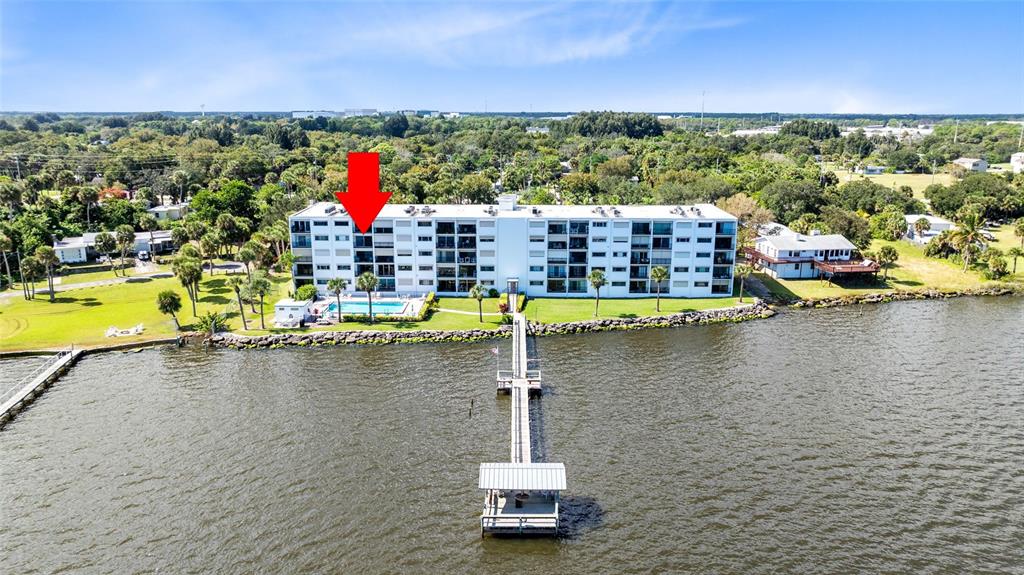 An aerial view shows a multi-story apartment building with a pool and a long pier — 3901 DIXIE HIGHWAY NE UNIT 409, PALM BAY, FL
