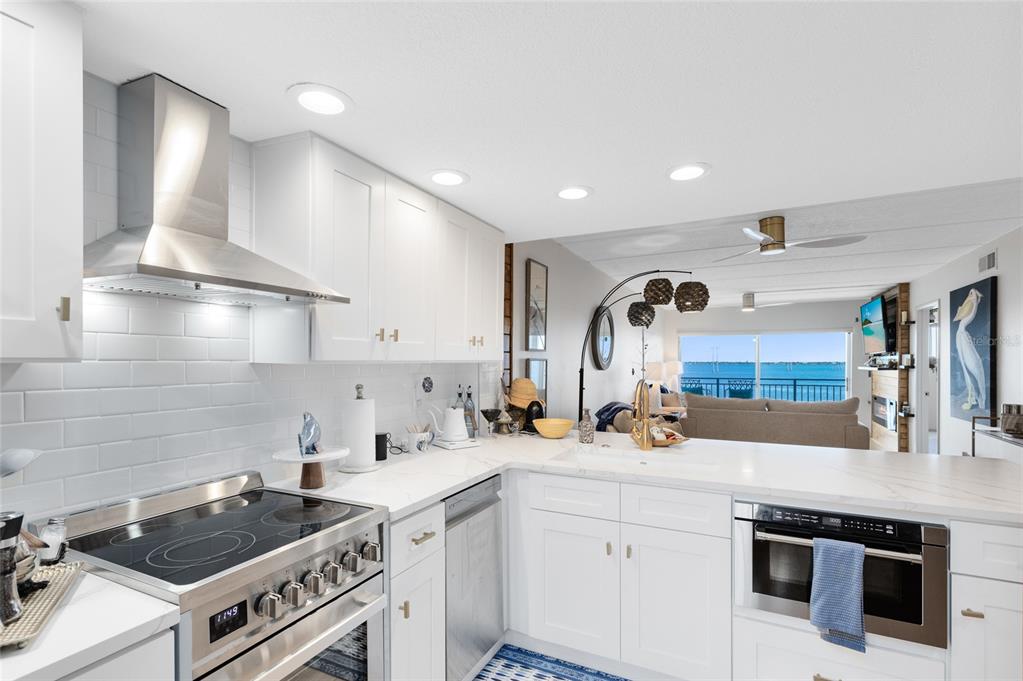 A modern white kitchen with stainless steel appliances overlooks a living area and water view — 3901 DIXIE HIGHWAY NE UNIT 409, PALM BAY, FL
