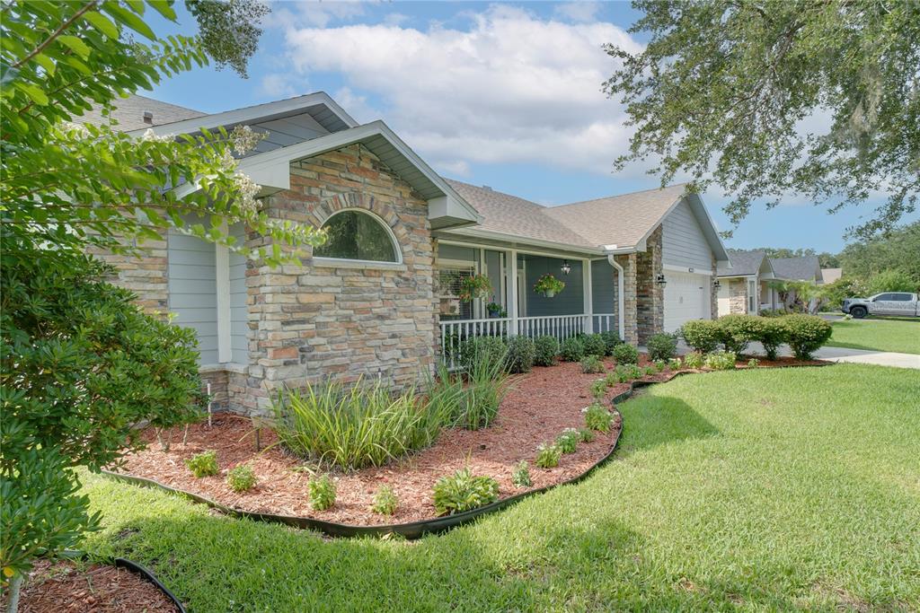 A single-story house with stone veneer siding, a covered porch, and a landscaped front yard — 123 RACHEL LIN LANE, ST CLOUD, FL