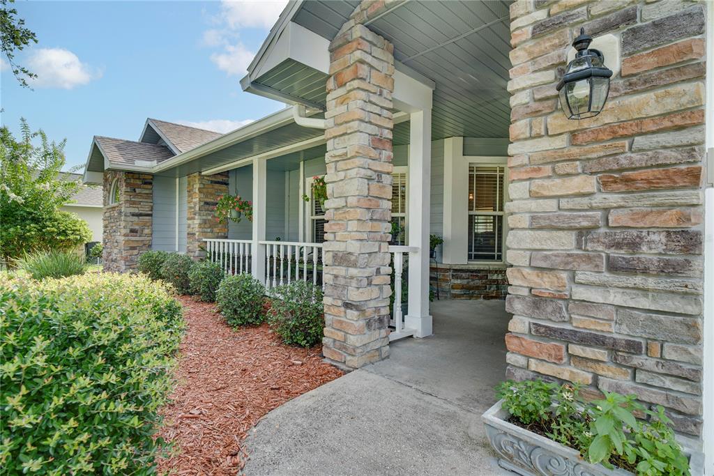 A covered front porch features stone pillars, white railings, and light blue siding — 123 RACHEL LIN LANE, ST CLOUD, FL