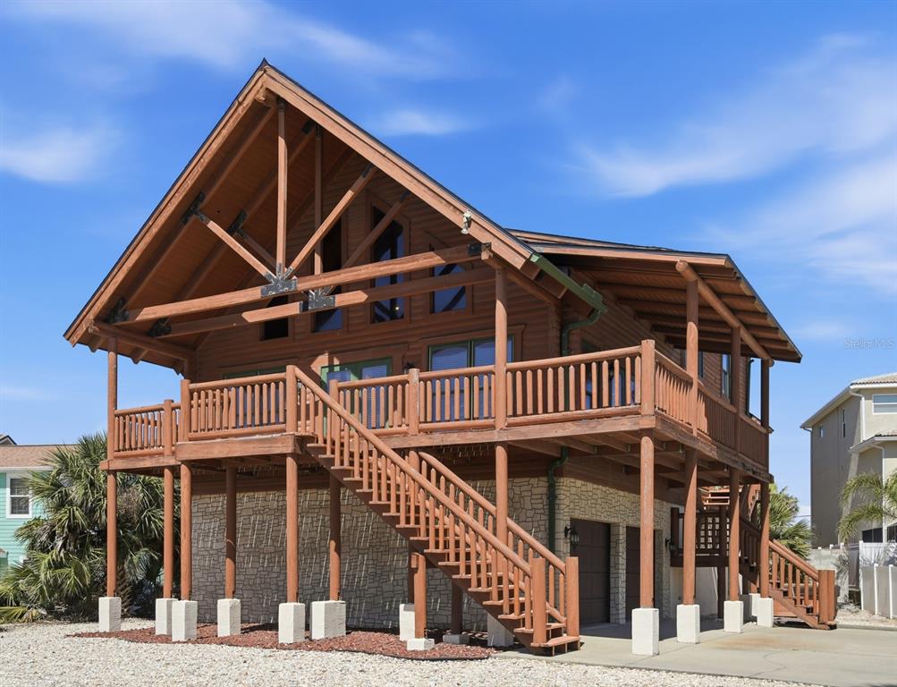A two-story wooden stilt house with a large deck and stone-faced ground level — 109 AVALON DRIVE, ORMOND BEACH, FL