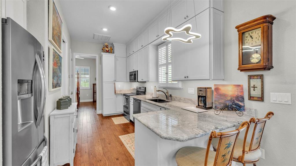 A kitchen features light gray cabinets, granite countertops, stainless steel appliances, and a breakfast bar — 3003 WOOD DUCK DRIVE, POLK CITY, FL