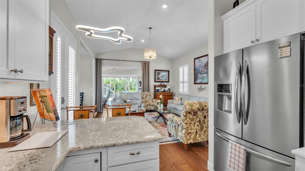 A kitchen with granite countertops overlooks a living room with a vaulted ceiling and patio doors — 3003 WOOD DUCK DRIVE, POLK CITY, FL