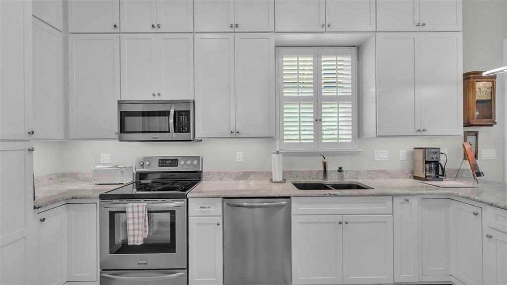 A kitchen with white cabinets, stainless steel appliances, and light-colored granite countertops — 3003 WOOD DUCK DRIVE, POLK CITY, FL